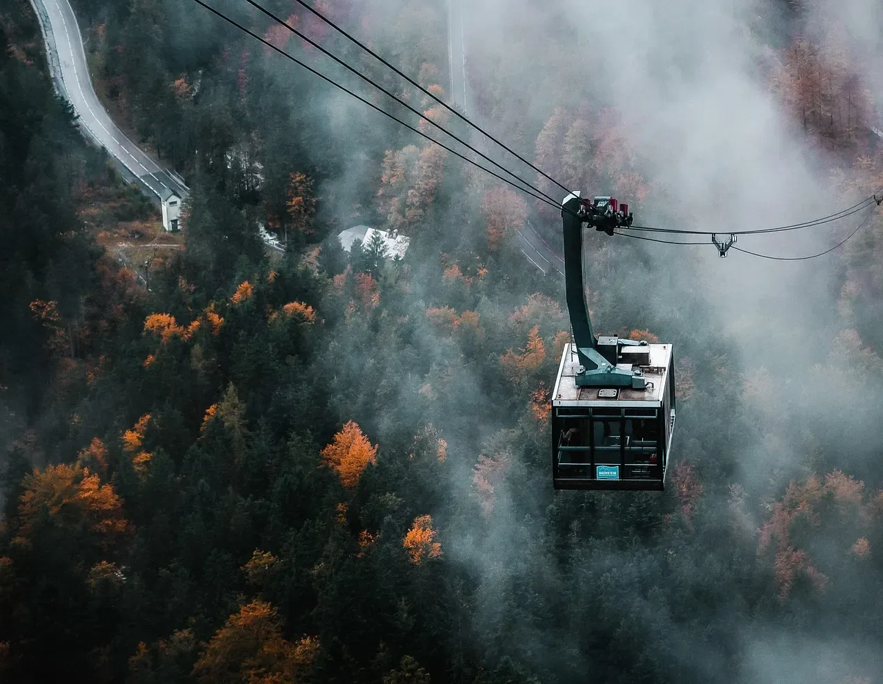 Pendelbahnkabine über herbstlichem Wald im Nebel
